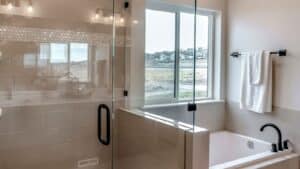 A modern bathroom with a tub and framed glass shower door.